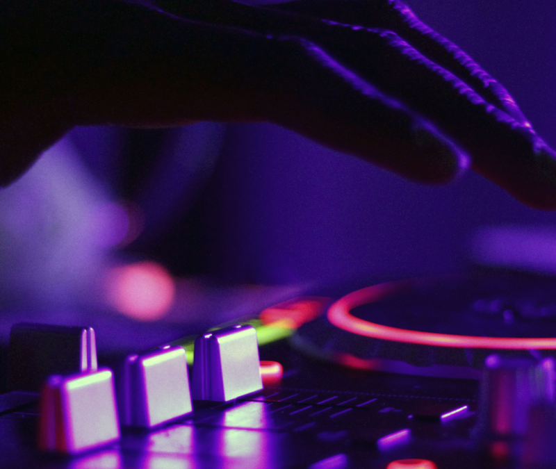 Close up image of a dj spinning turntables in a low lit club scene.
