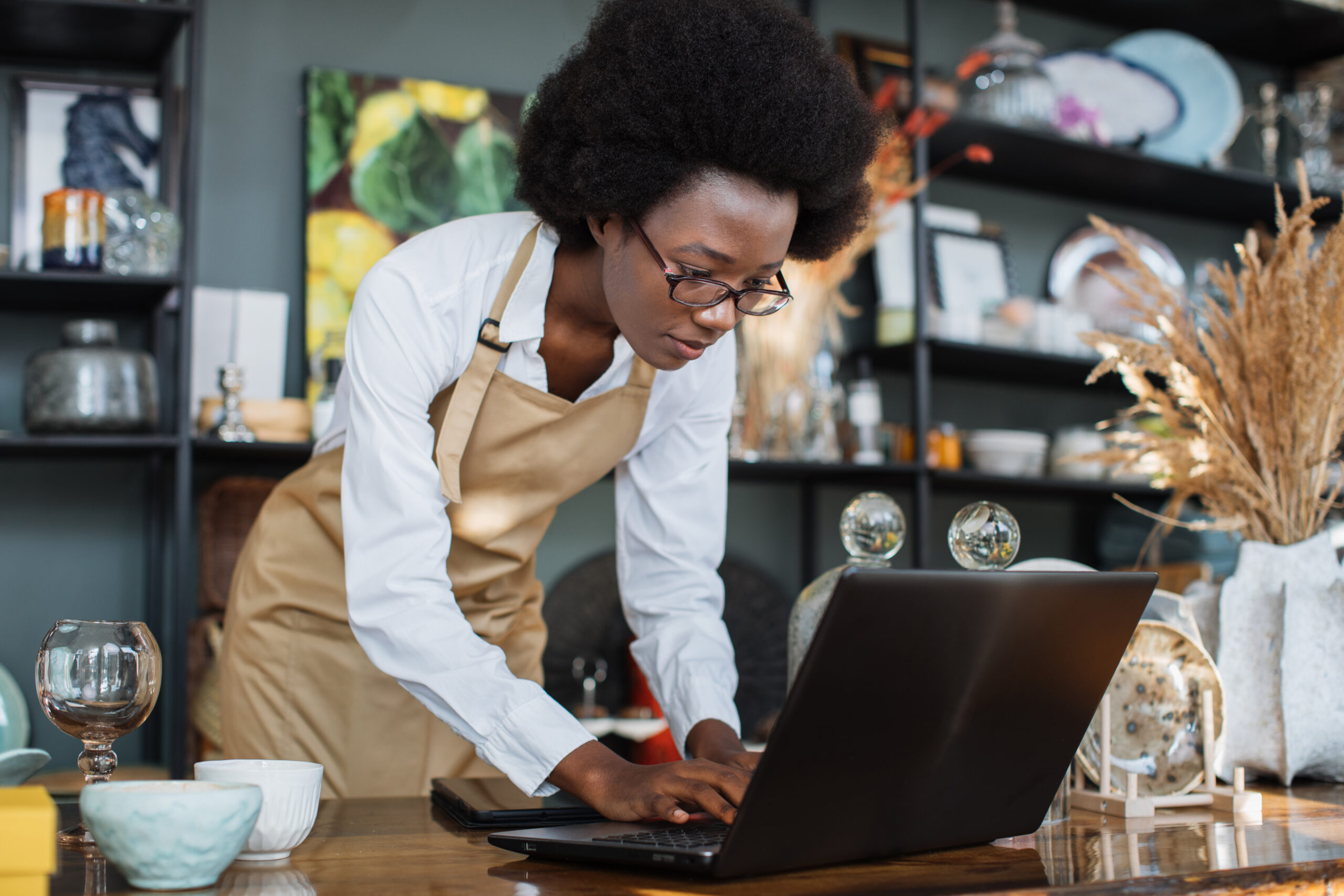 Afro american woman using laptop for work at shop