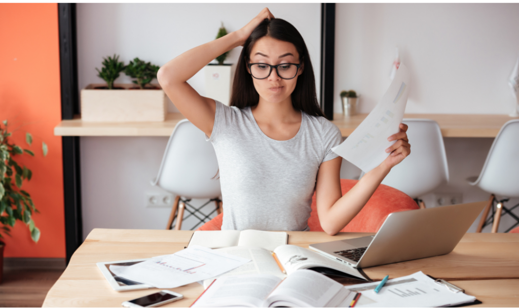 Woman scratching her head while reviewing marketing strategy paperwork